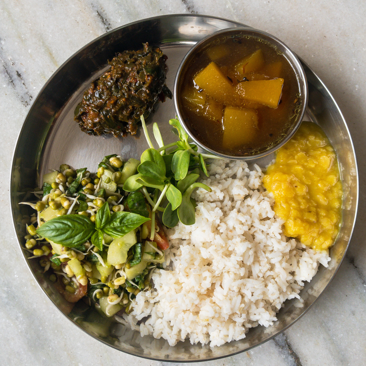 Plate of mung sprouts salad, rasam, dal, and rice with chutney.