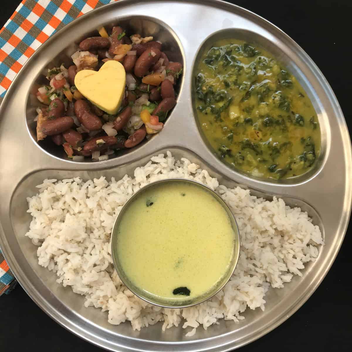 Lunch plate with rajma salad, coconut rasam, spinach dal, and rice.