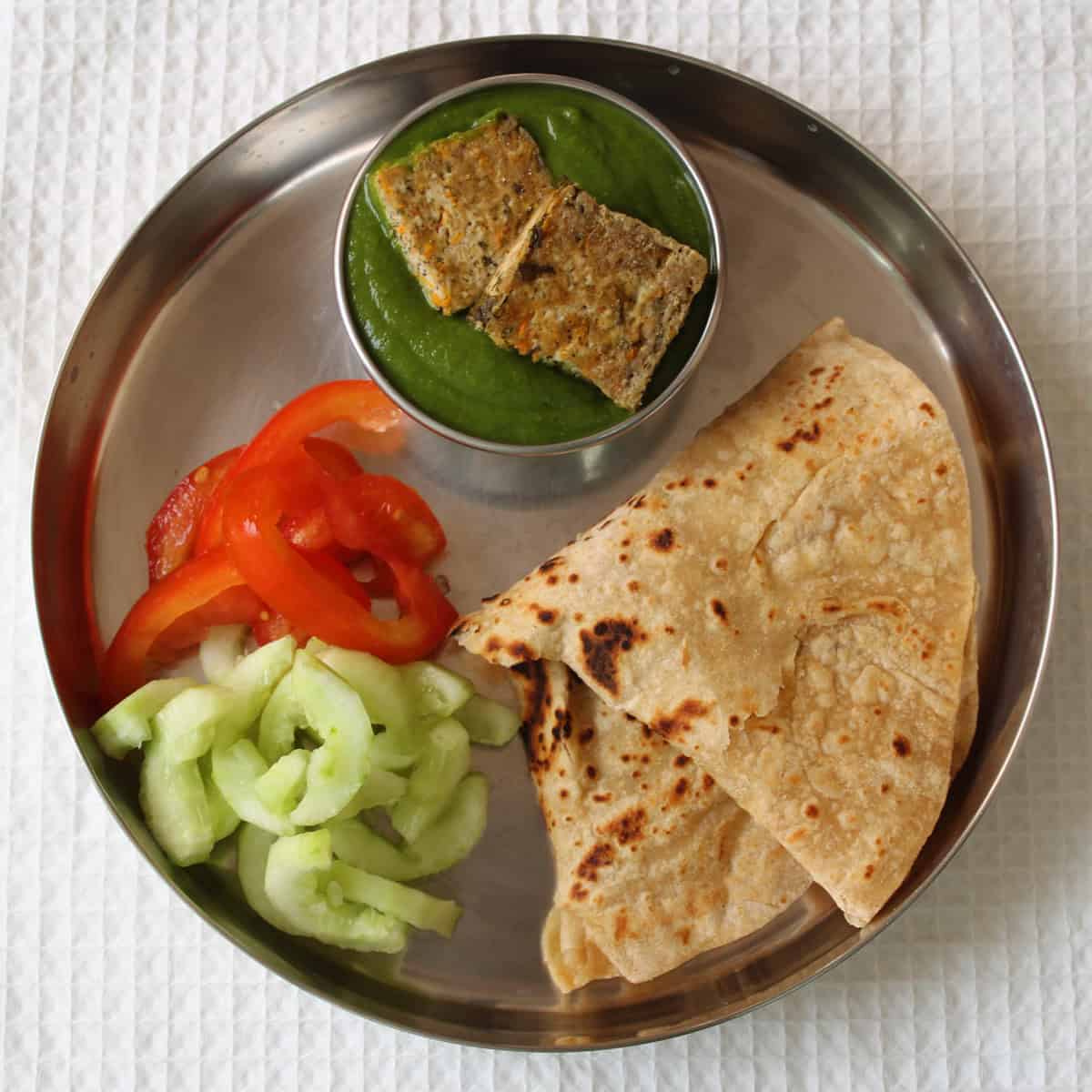 Indian lunch plate with roti, saag tofu curry, and salad.