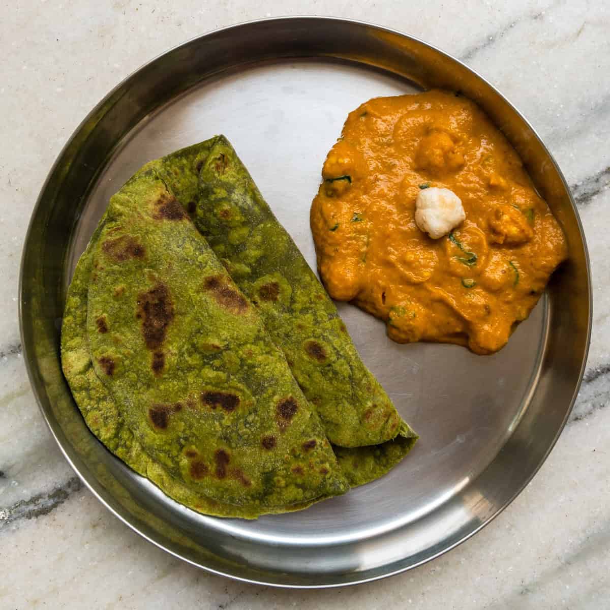 Lunch plate with spinach paratha and creamy makhana cashew curry.