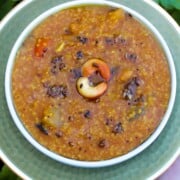 A bowl of Instant Pot Bisi Bele Bath garnished with cashews and spices, served on a green plate.