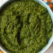 A bowl of vibrant green Indian spinach saag on a colorful checkered napkin.