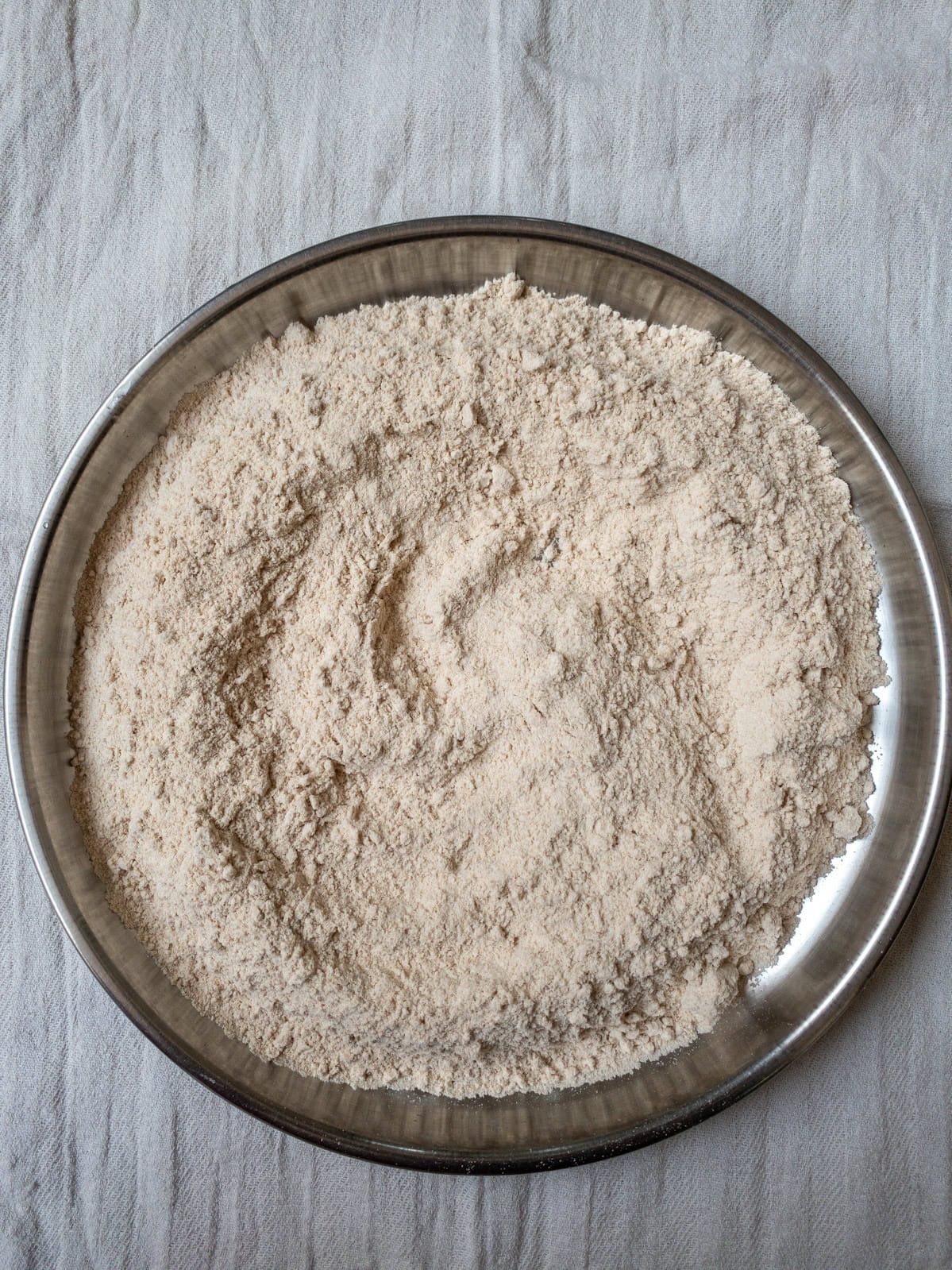 Whole wheat flour in a steel plate, ready for making chapati dough.