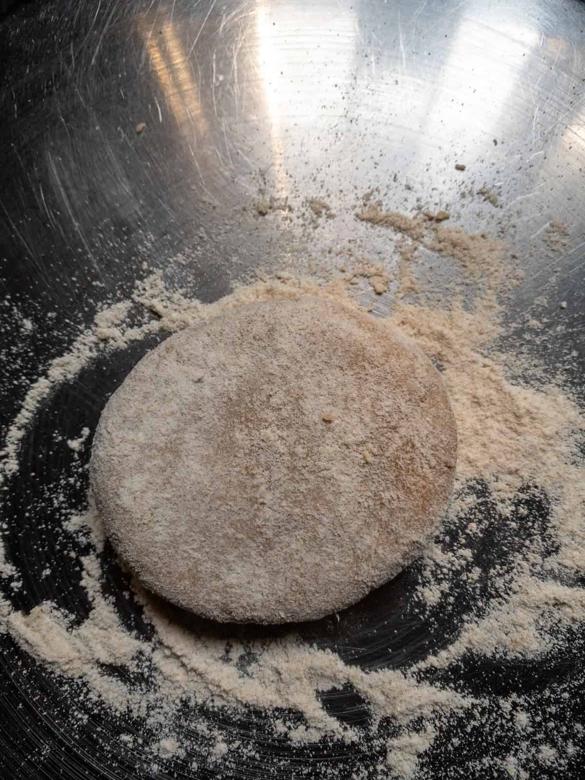 A single chapati dough ball coated with dry flour before rolling.