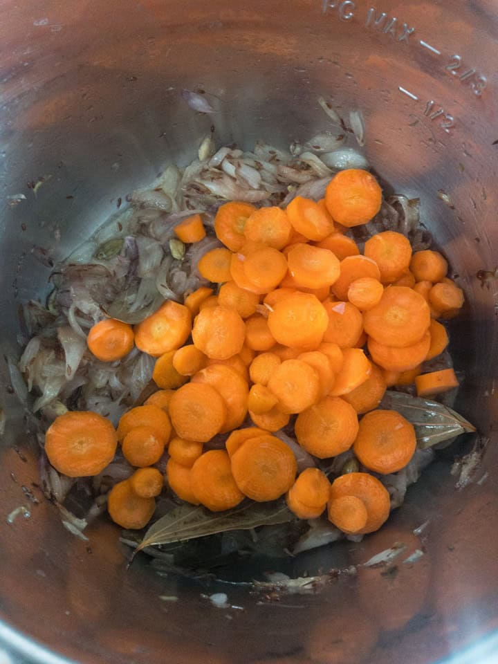 Carrot rounds piled on top of sautéed onions inside the pot.