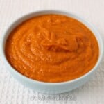 Creamy orange Instant Pot curry sauce in a white bowl on a light textured background.