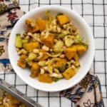 Close-up of black-eyed peas and roasted butternut squash salad in a white bowl placed on a checkered cloth.