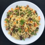 A white plate filled with chickpea millet rice stir fry, garnished with fresh coriander.
