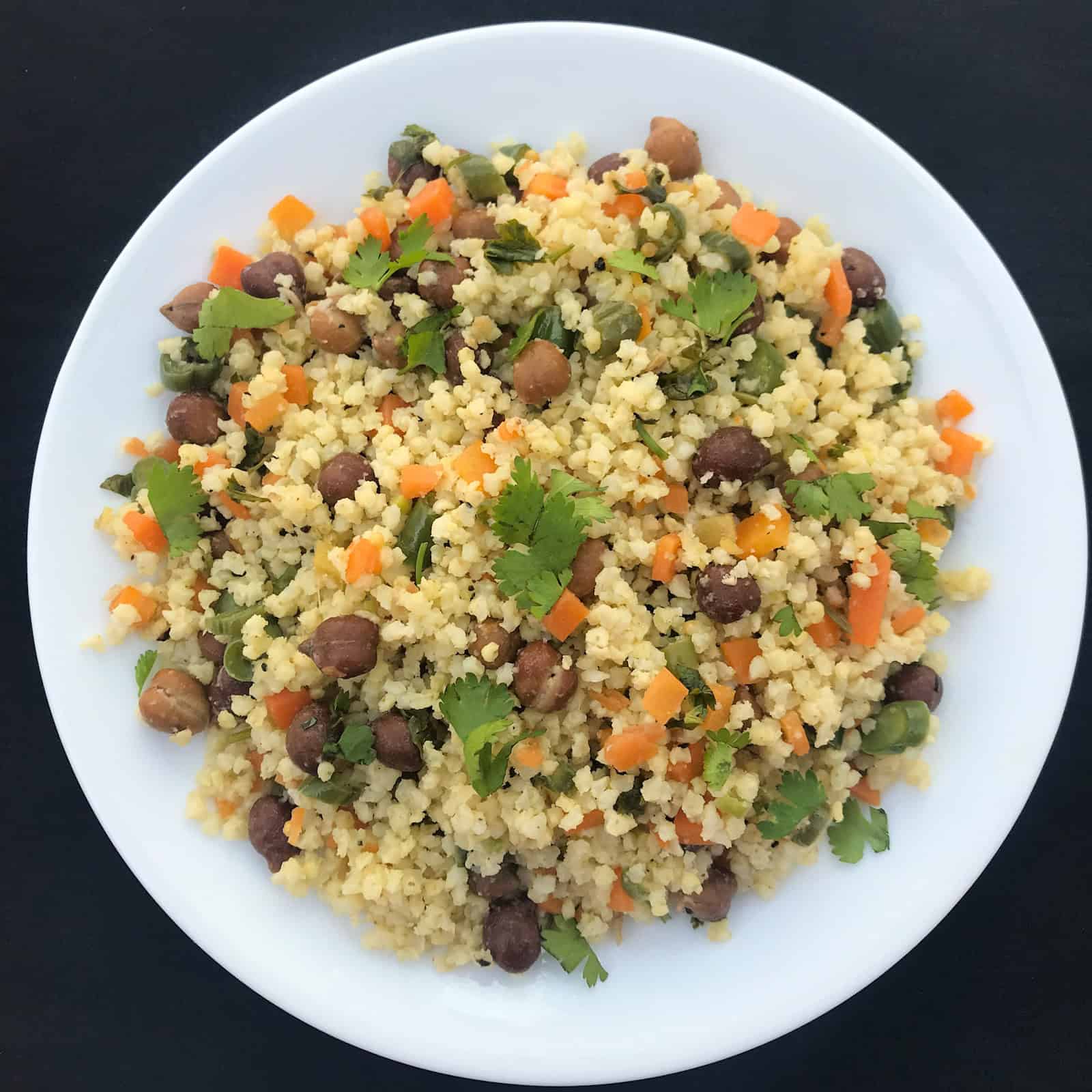 A white plate filled with chickpea millet rice stir fry, garnished with fresh coriander.