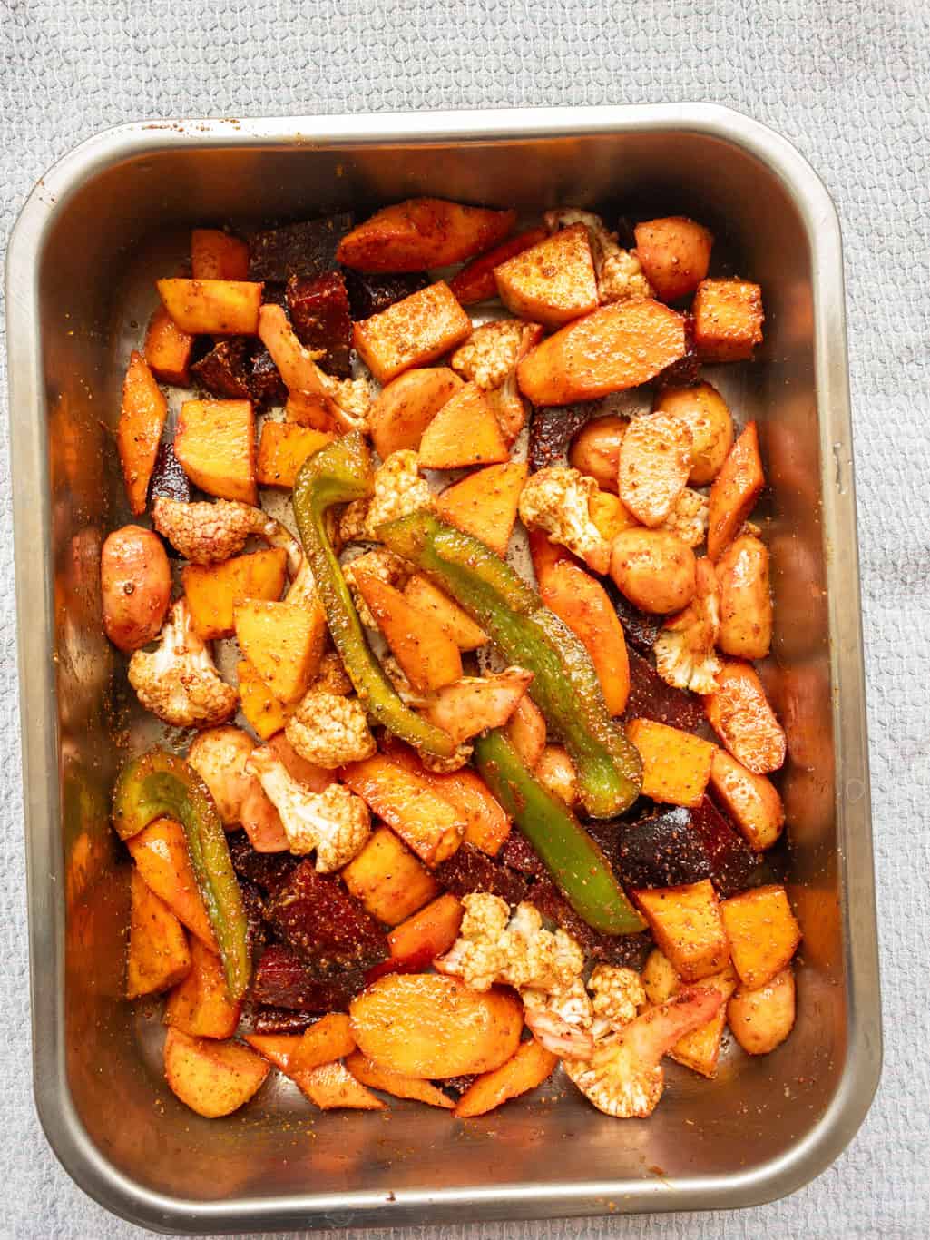 Mixed vegetables coated with Indian spices and oil, ready to go into the oven.