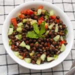 Bowl of Indian kala chana salad with cucumber, tomato, onion, and mint garnish.