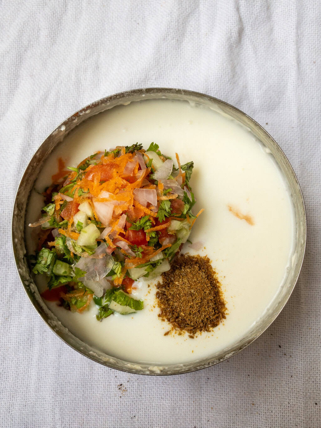 Whisked yogurt with added vegetables, grated carrot, and cumin powder.