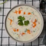 Indian yogurt sauce (raita) served in a bowl, garnished with cilantro and red chili oil, perfect side dish for biryani and pulao.