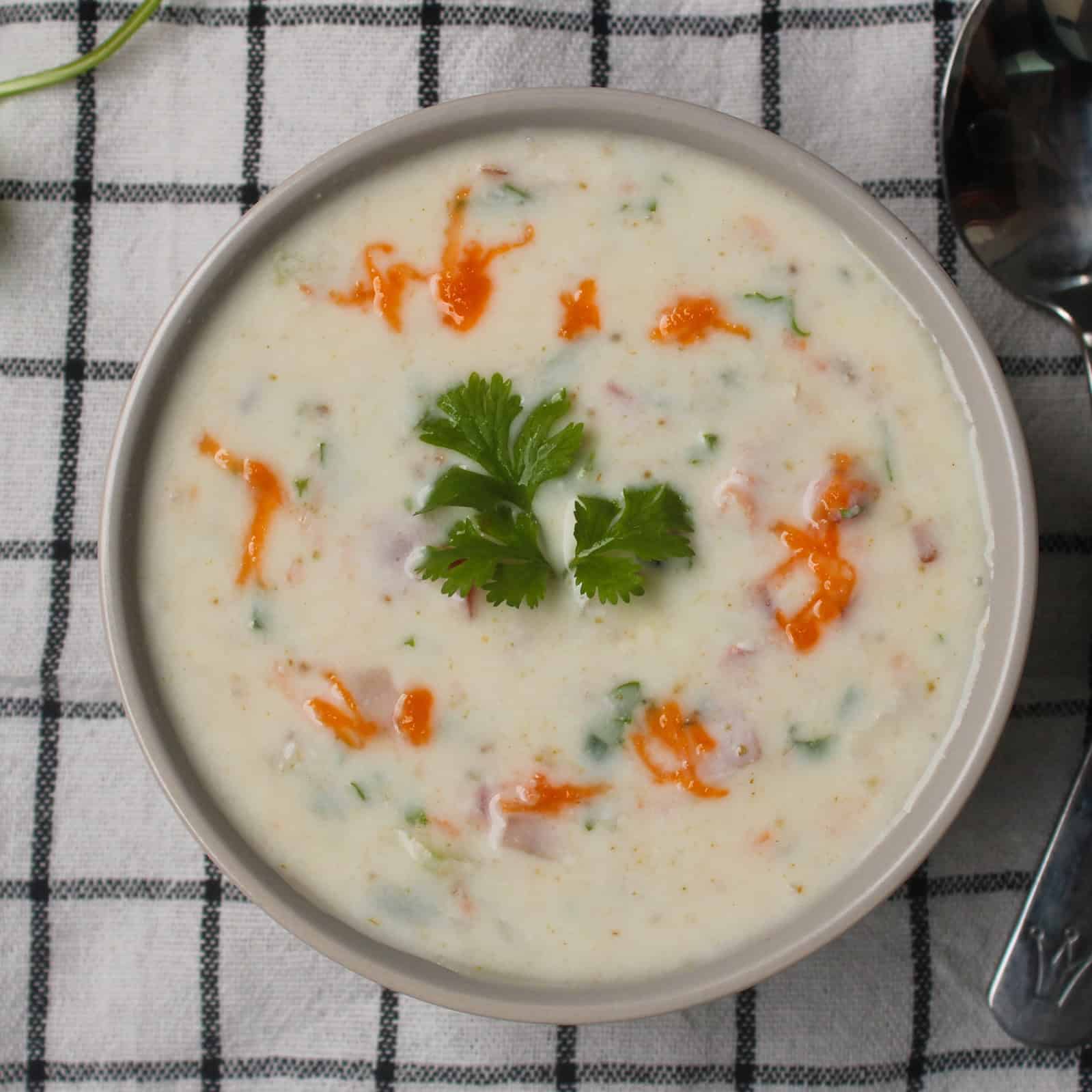 Indian yogurt sauce (raita) served in a bowl, garnished with cilantro and red chili oil, perfect side dish for biryani and pulao.