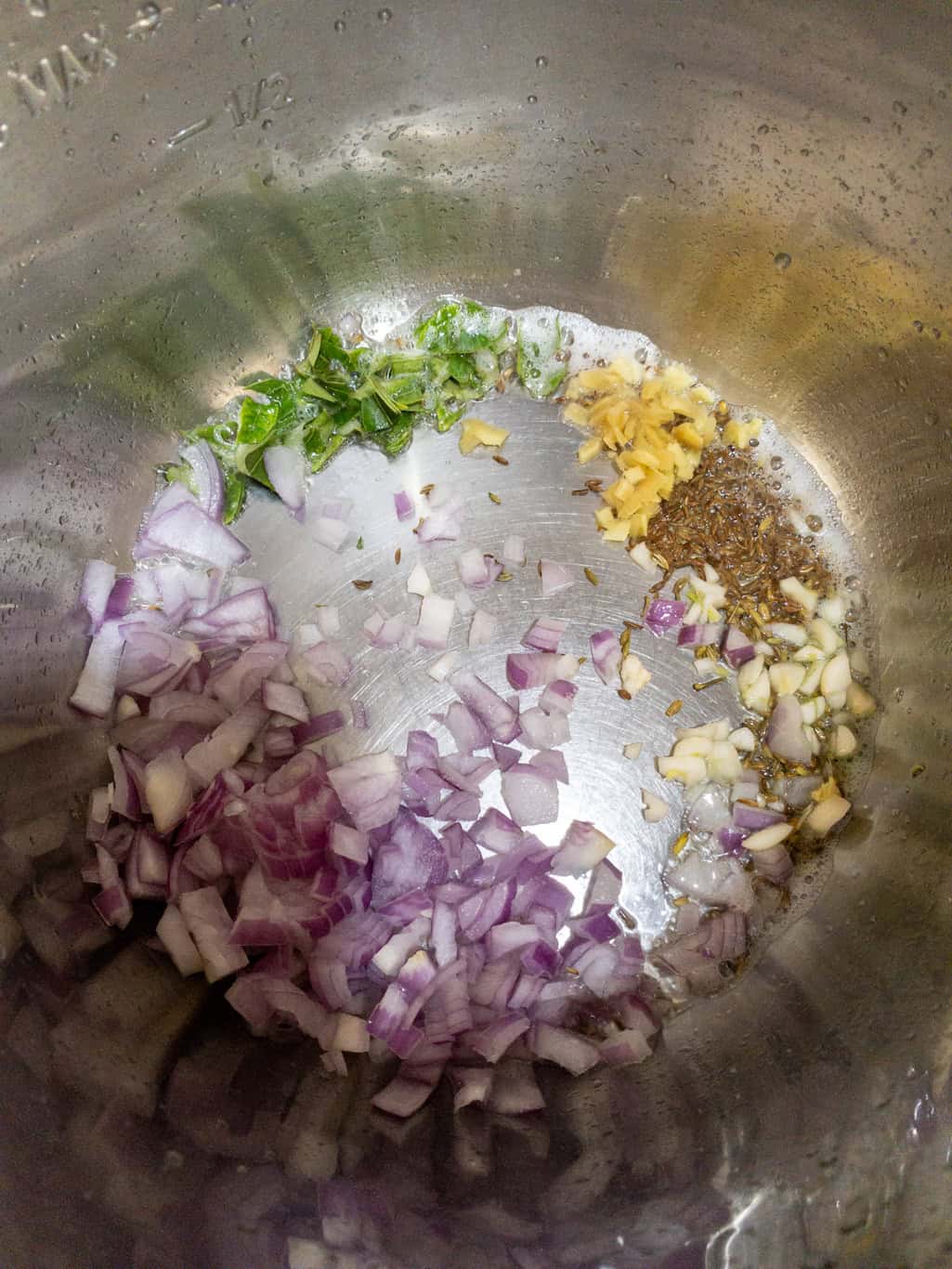 Chopped onions, garlic, ginger, and curry leaves added to tempered cumin seeds in the Instant Pot.