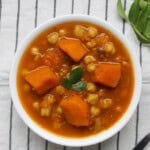 Close-up of Indian pumpkin chickpea curry in a white bowl showing tender pumpkin pieces and chickpeas in rich spiced gravy.