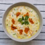 Overhead shot of pumpkin raita showing its creamy texture with grated pumpkin, herbs, and a cilantro garnish.