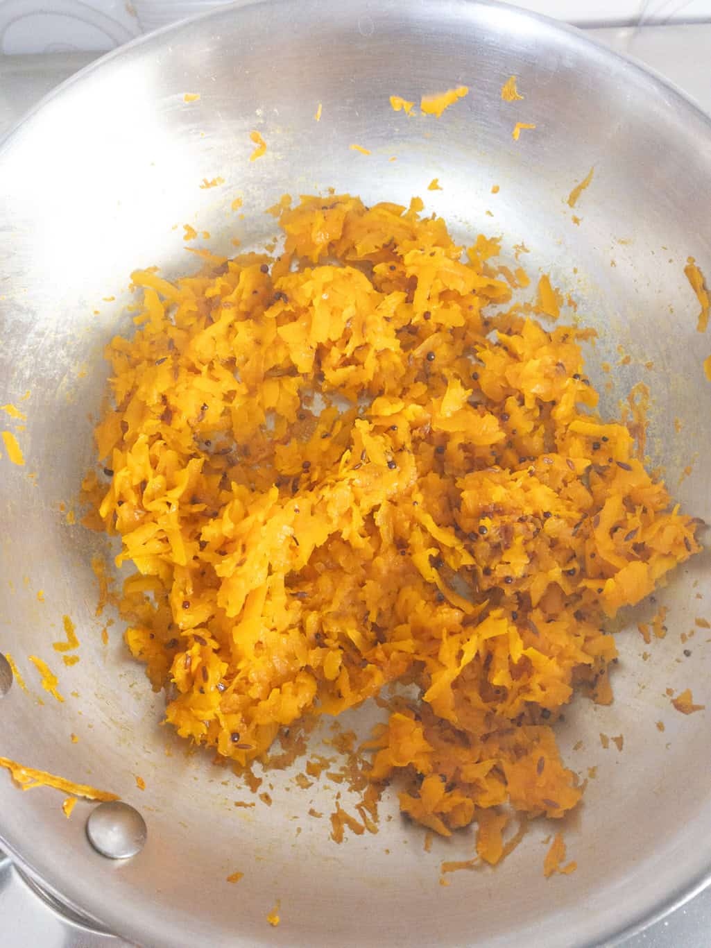 Cooked grated pumpkin in the pan after sautรฉing with spices for pumpkin raita preparation.