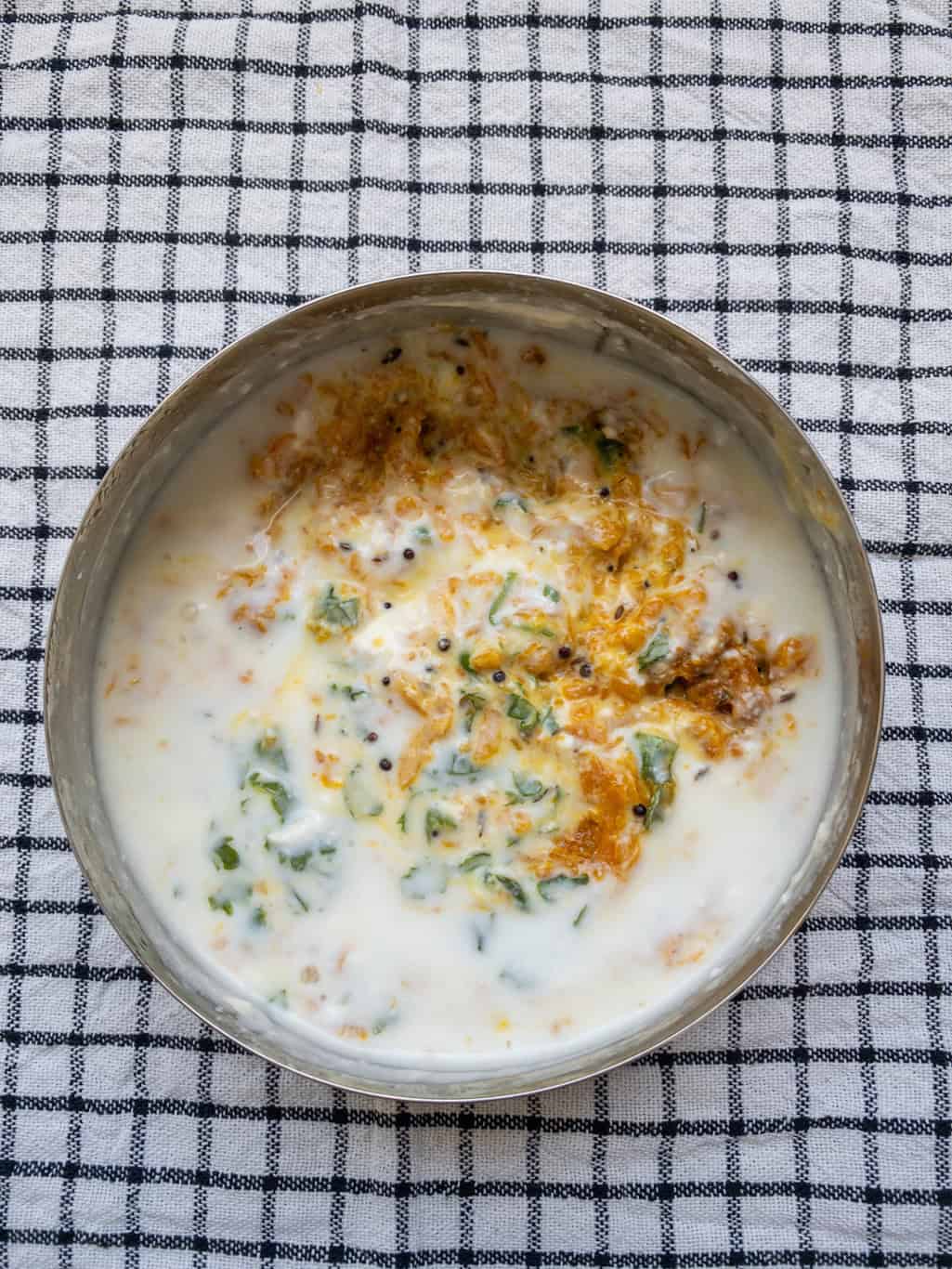 Pumpkin raita fully mixed, showing curd combined with cooked pumpkin and spices in a steel bowl.