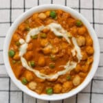 Chickpea tikka masala garnished with cream and green peas.