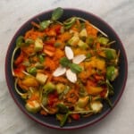 Top view of fresh vegetable salad with cucumber, bell peppers, carrot, and sunflower sprouts.