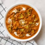 Creamy cauliflower tikka masala served in a white bowl with cashew cream and roasted florets.