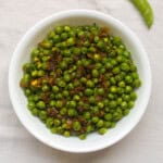 Indian spiced sautéed green peas served warm in a white bowl.