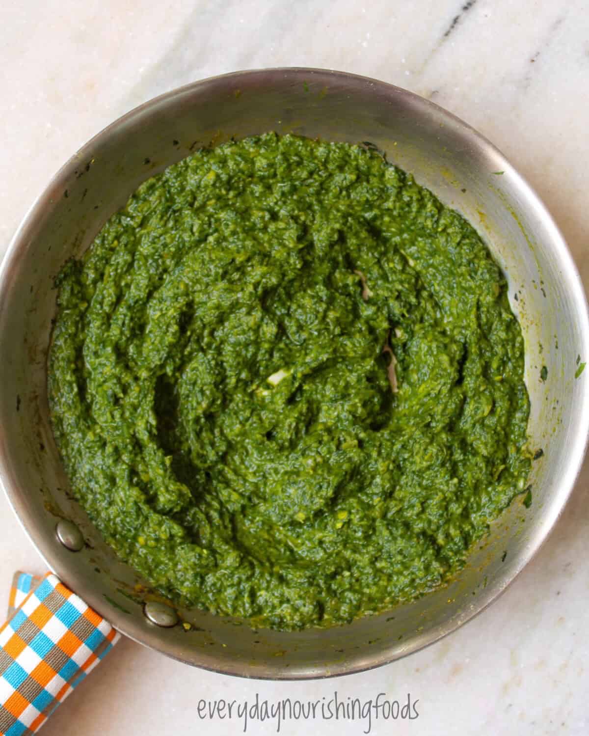 Homemade Indian spinach saag base cooked with onions, spices, ginger, and garlic in a pan.