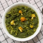 Saag gobi served in a white bowl with roasted cauliflower florets in spinach curry.