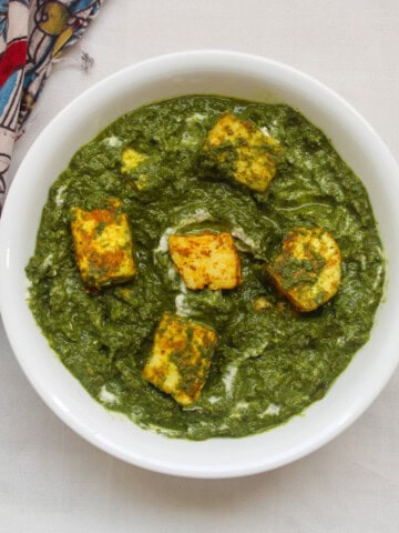 Close-up of saag paneer showing roasted paneer cubes in thick spinach gravy.