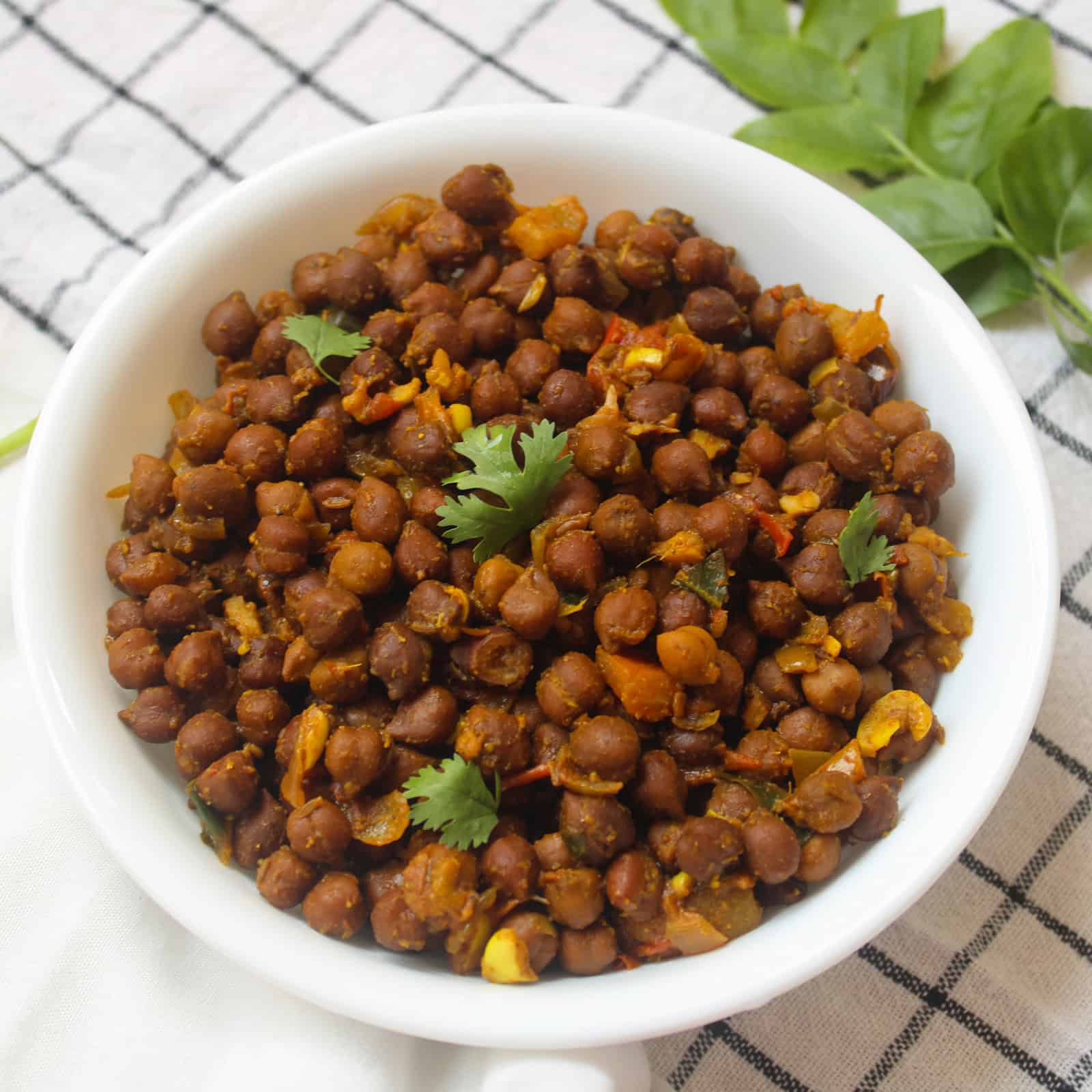 Close view of black chickpea masala with tomato masala and coriander garnish.