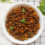 Finished black chickpea masala served in a white bowl with fresh coriander leaves.