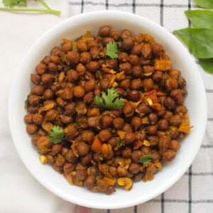 Finished black chickpea masala served in a white bowl with fresh coriander leaves.