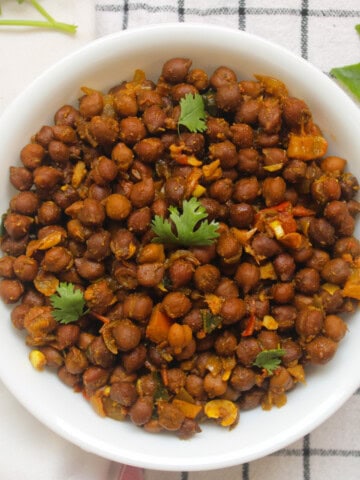 Finished black chickpea masala served in a white bowl with fresh coriander leaves.