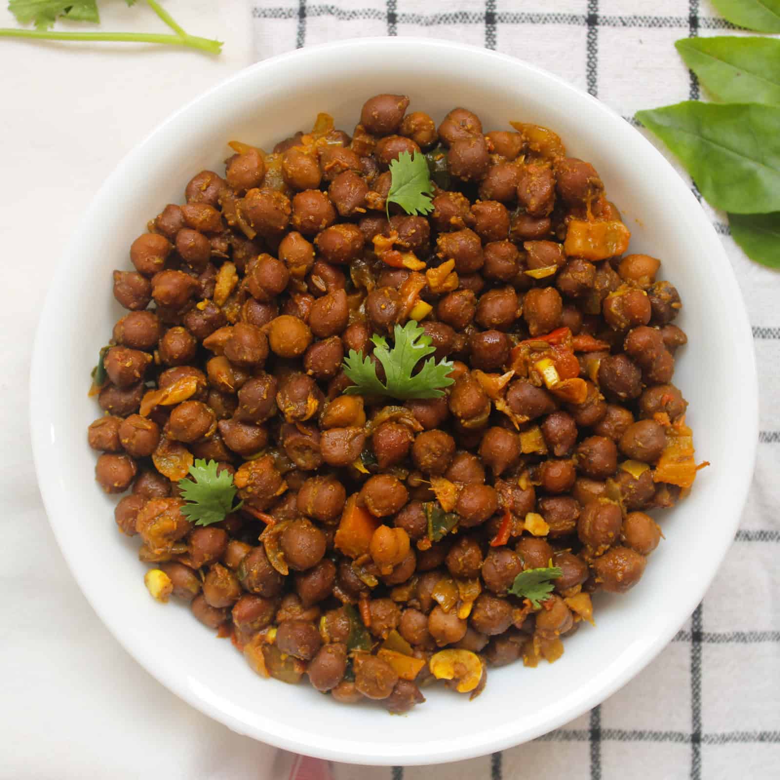 Finished black chickpea masala served in a white bowl with fresh coriander leaves.