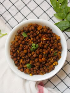 Black chickpea masala served in a white bowl with fresh coriander leaves.