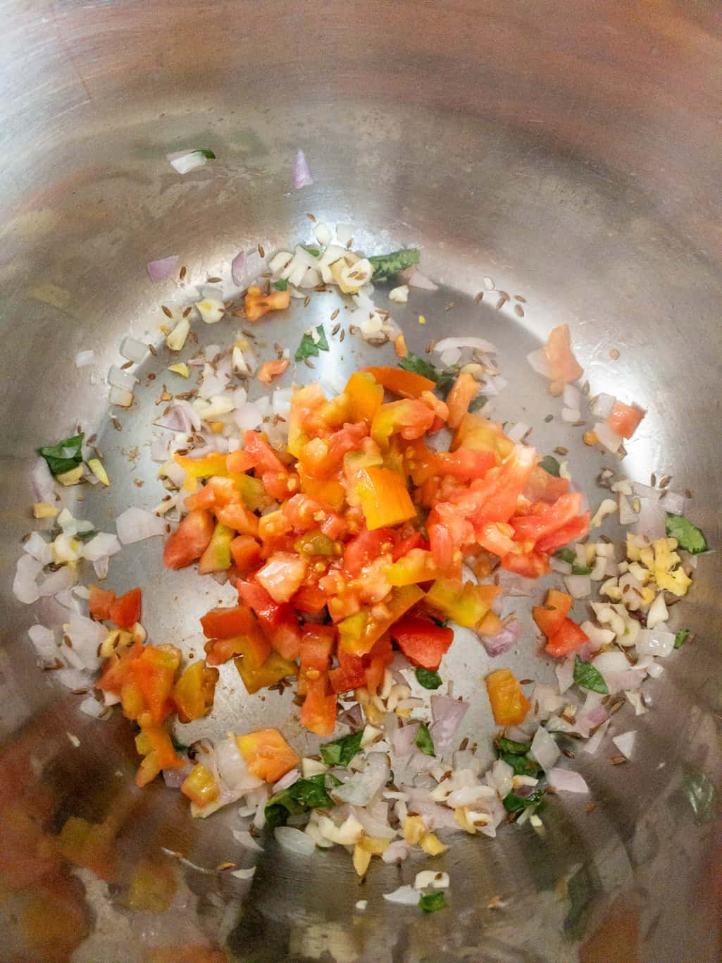 Chopped tomatoes added to sautéed onion, ginger, garlic, cumin seeds, and curry leaves.