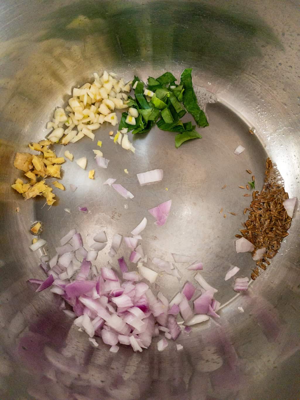 Chopped onion, ginger, garlic, curry leaves, and cumin seeds sautéing in oil.