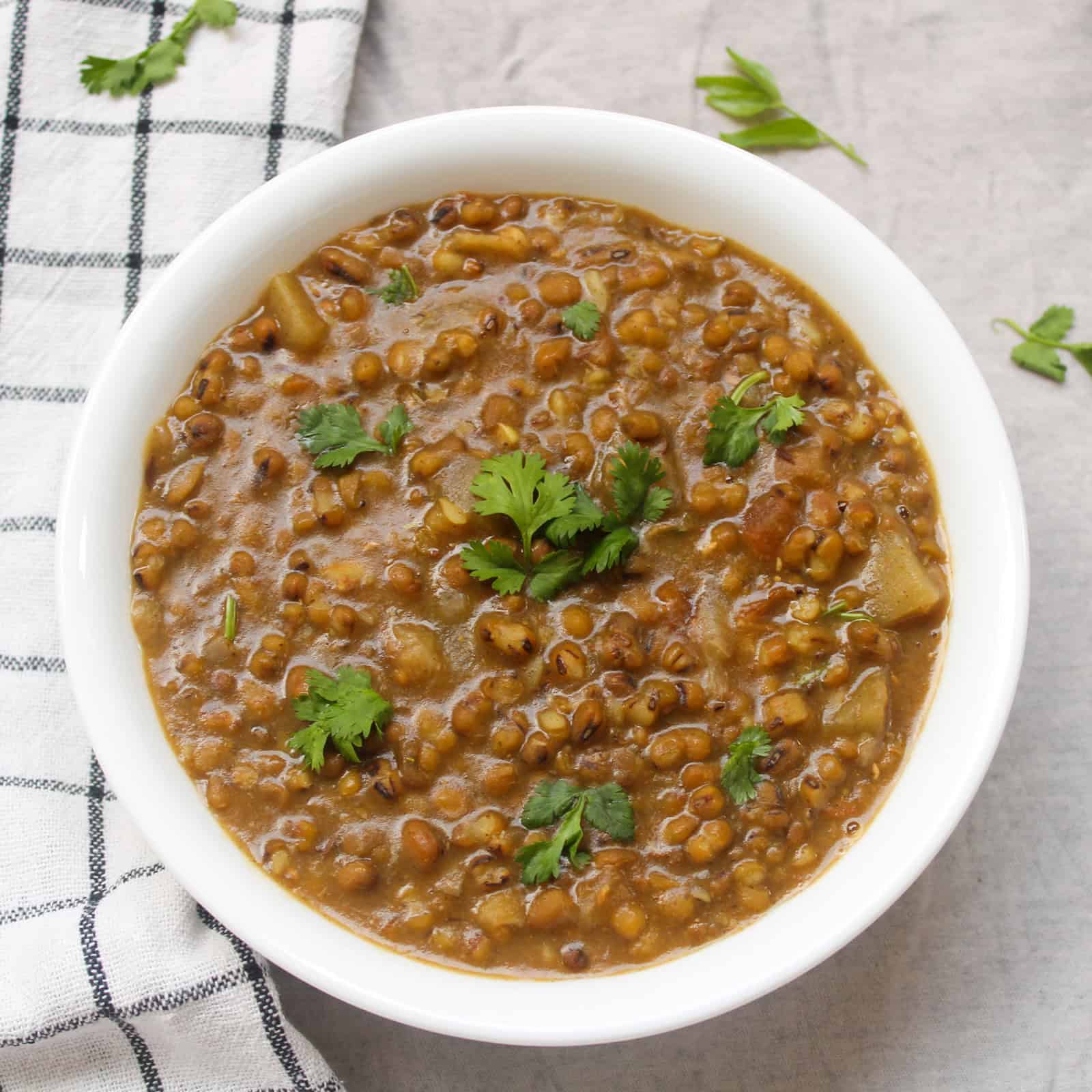 Green moong curry served in a white bowl with coriander garnish.
