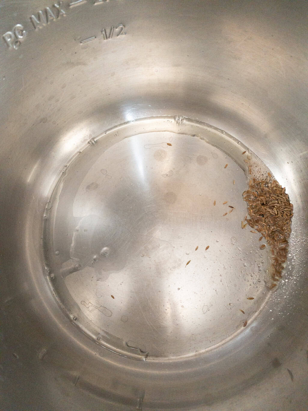 Cumin seeds sizzling in hot oil in the Instant Pot inner pot.