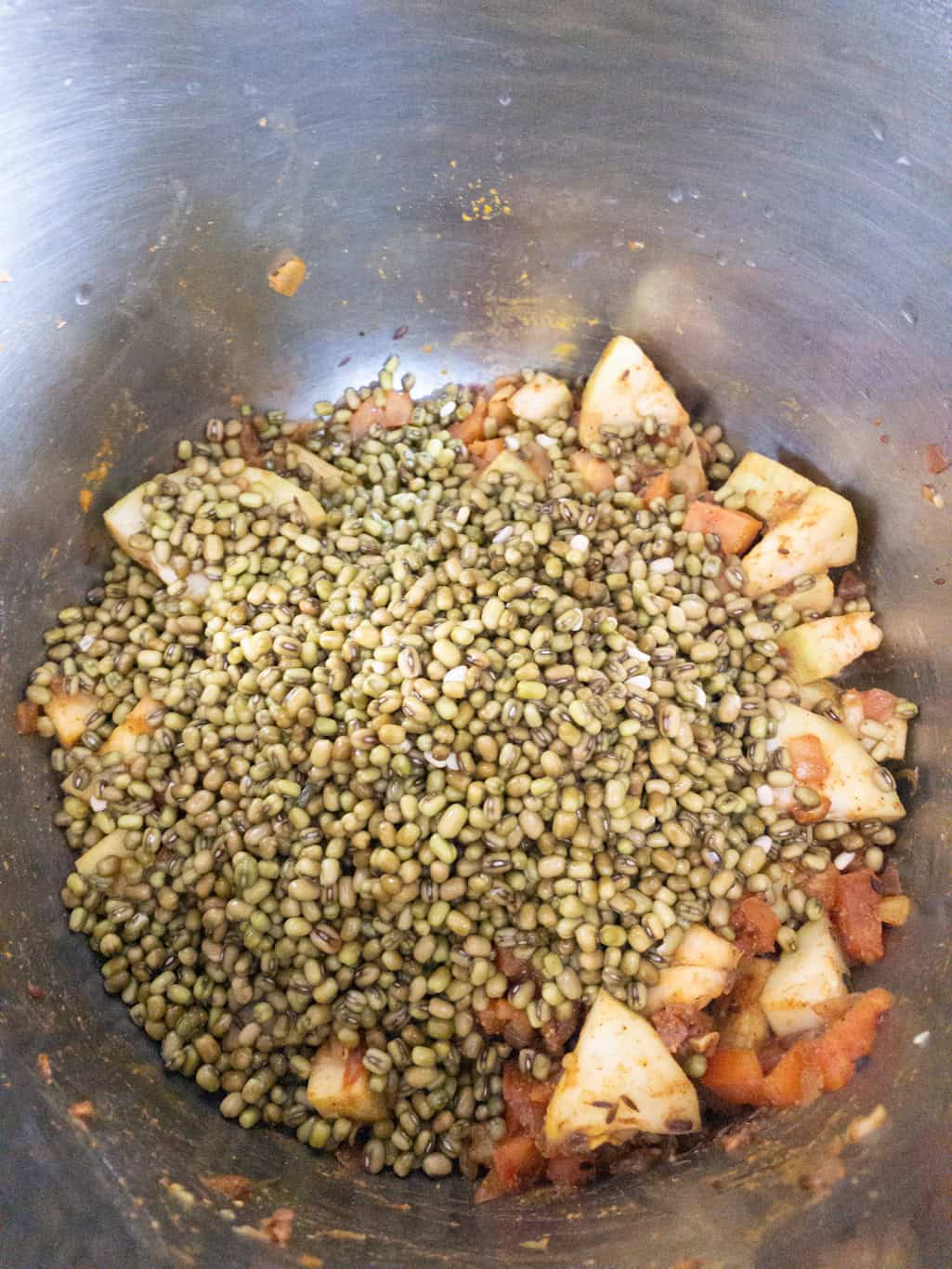 Rinsed whole moong beans poured over the spiced onion tomato masala in the Instant Pot.