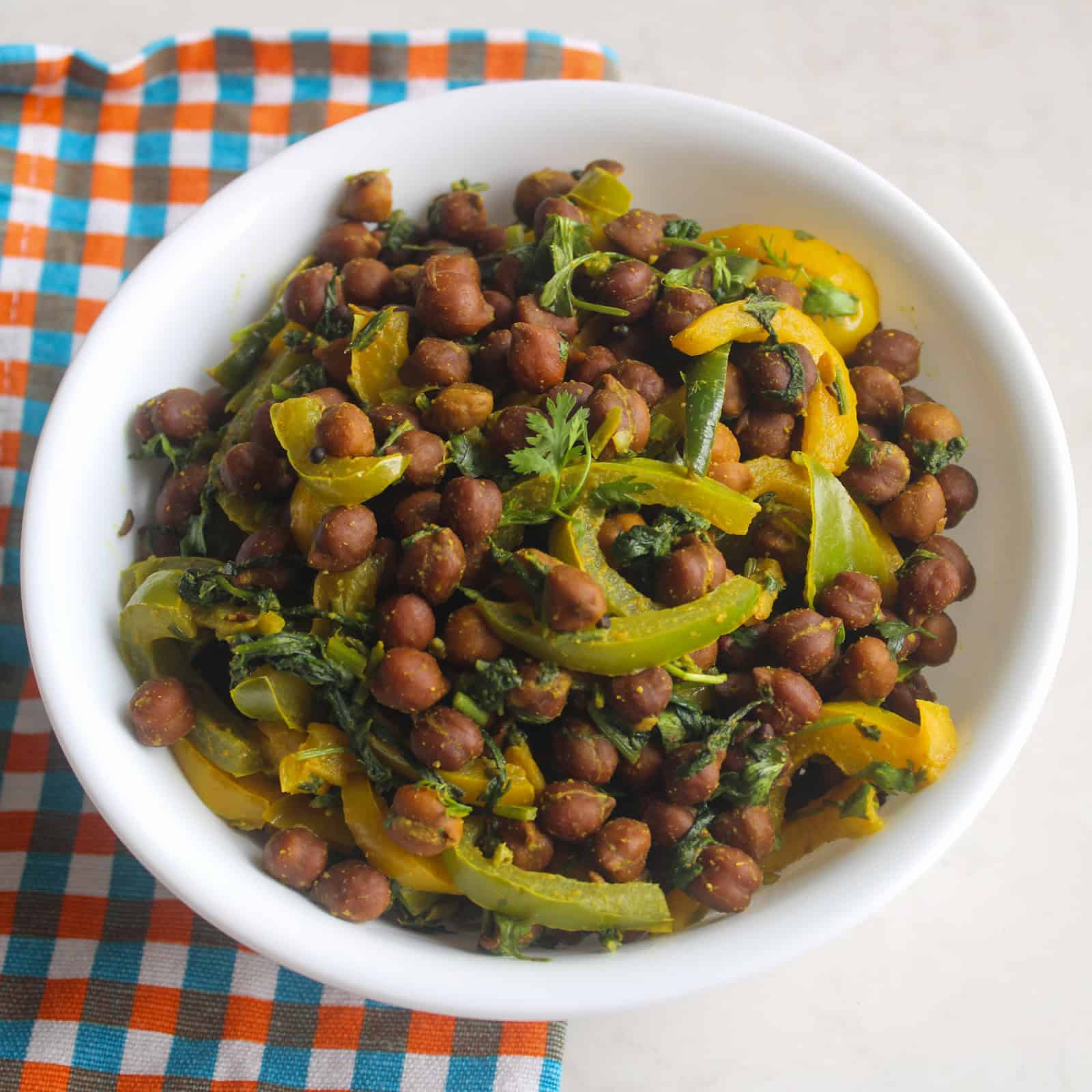 Indian bell pepper kala chana curry with spinach served in a white bowl.