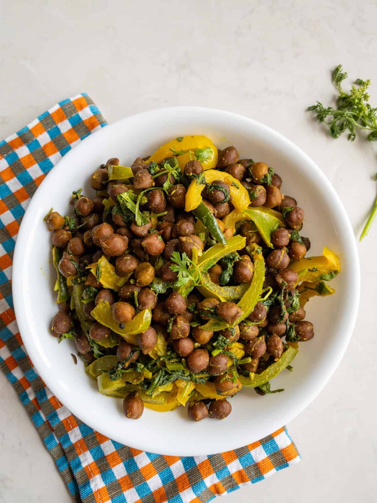 Indian bell pepper kala chana curry served in a white bowl with cilantro garnish.