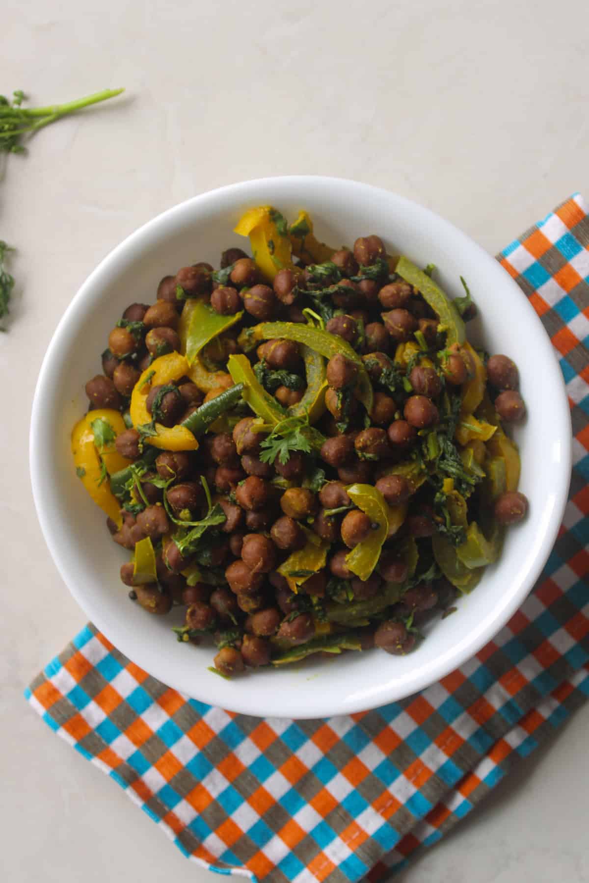 Bell pepper spinach kala chana curry served in a white bowl for an Indian meal.