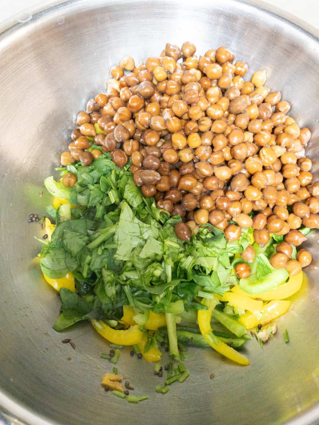 Cooked black chickpeas and chopped spinach added over bell peppers.