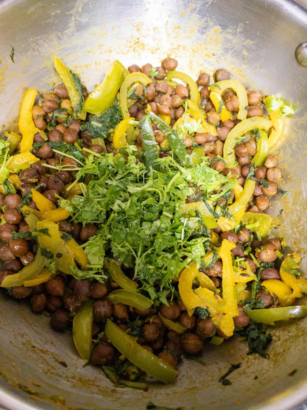 Fresh cilantro added over cooked kala chana and bell pepper curry.