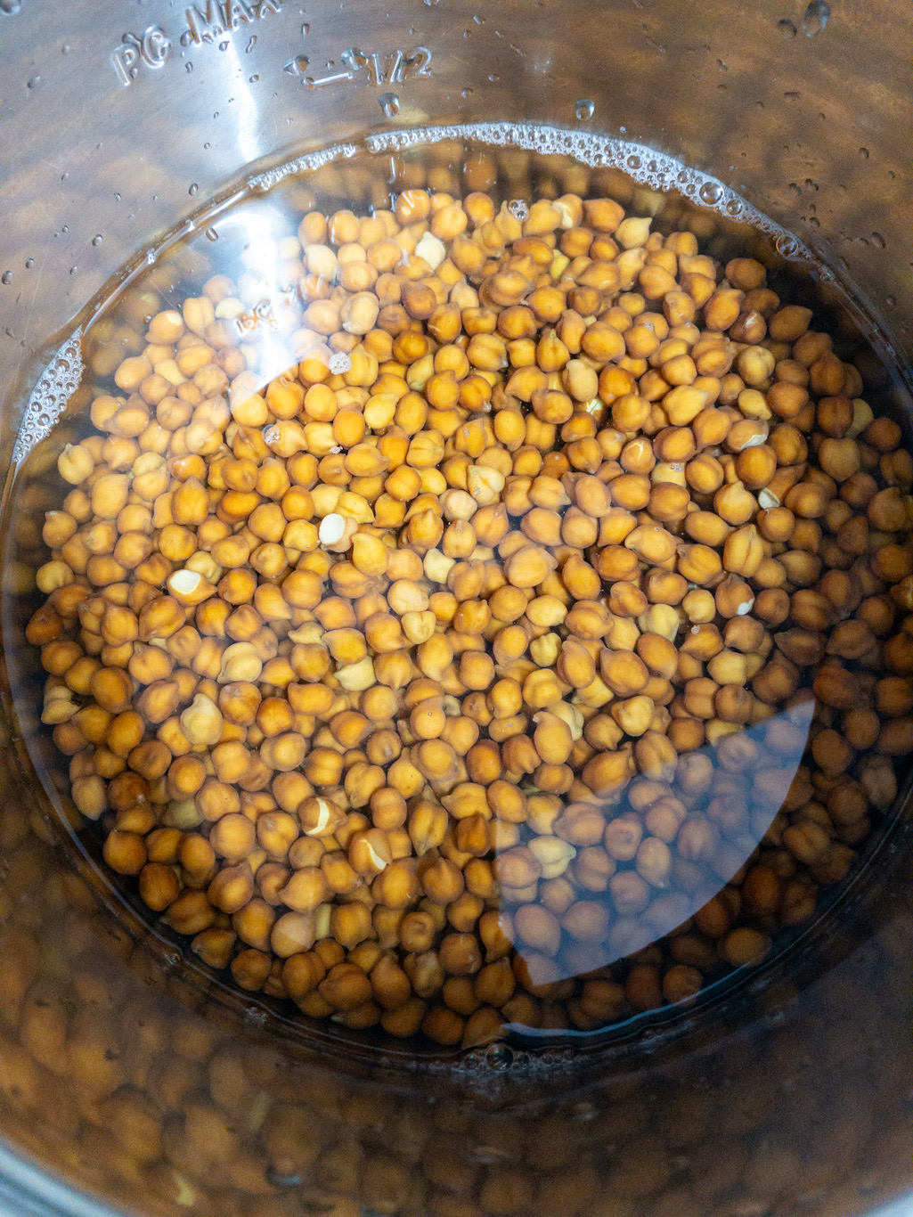 Brown chickpeas with water inside an Instant Pot insert.