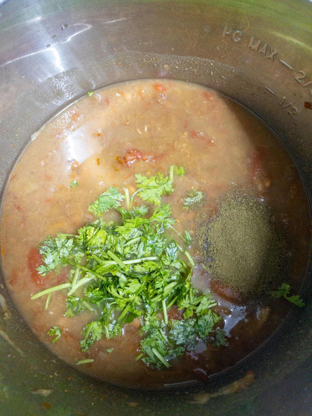 Cilantro leaves and kasuri methi powder are added to cooked rajma masala in the Instant Pot.