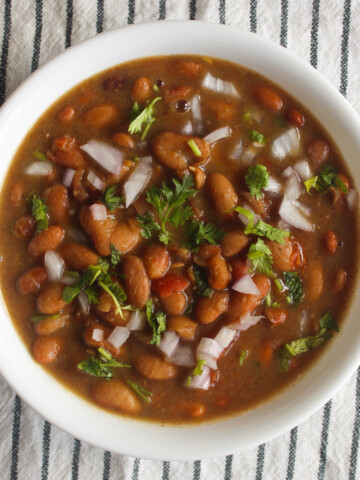 Instant Pot rajma masala served in a white bowl with onion and cilantro garnish.