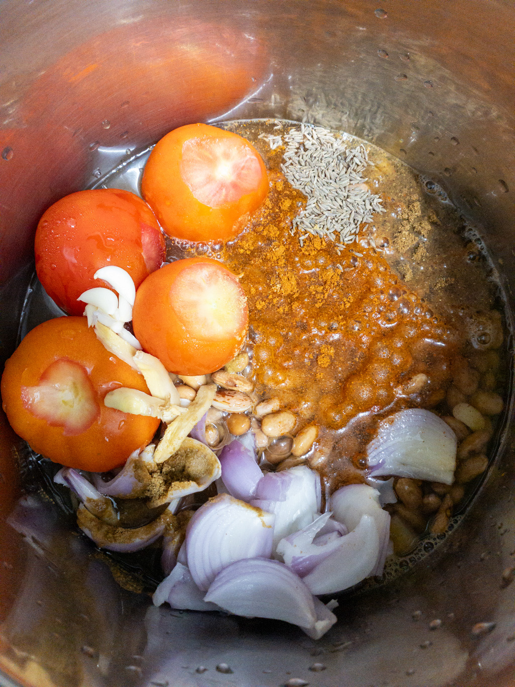 Soaked kidney beans are topped with tomatoes, onions, ginger, garlic, salt, spice powders, and water.